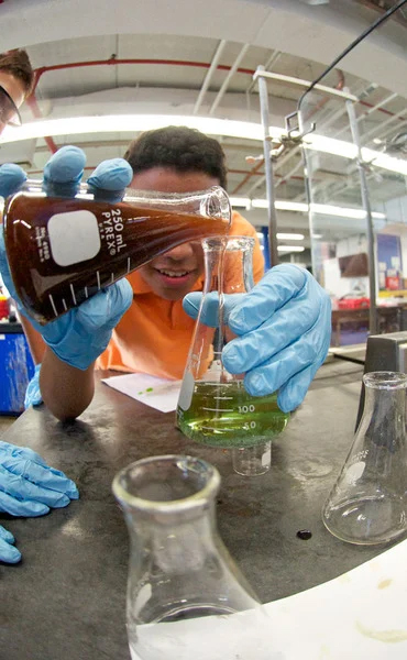 student pouring chemicals into beaker