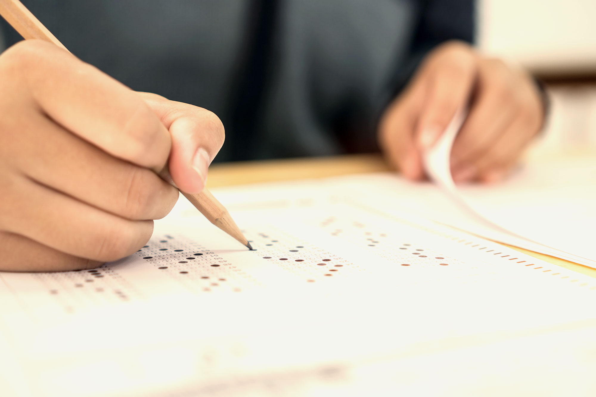 Tips for test taking. The image shows hands holding a pencil filling out answers in a scannable paper test.