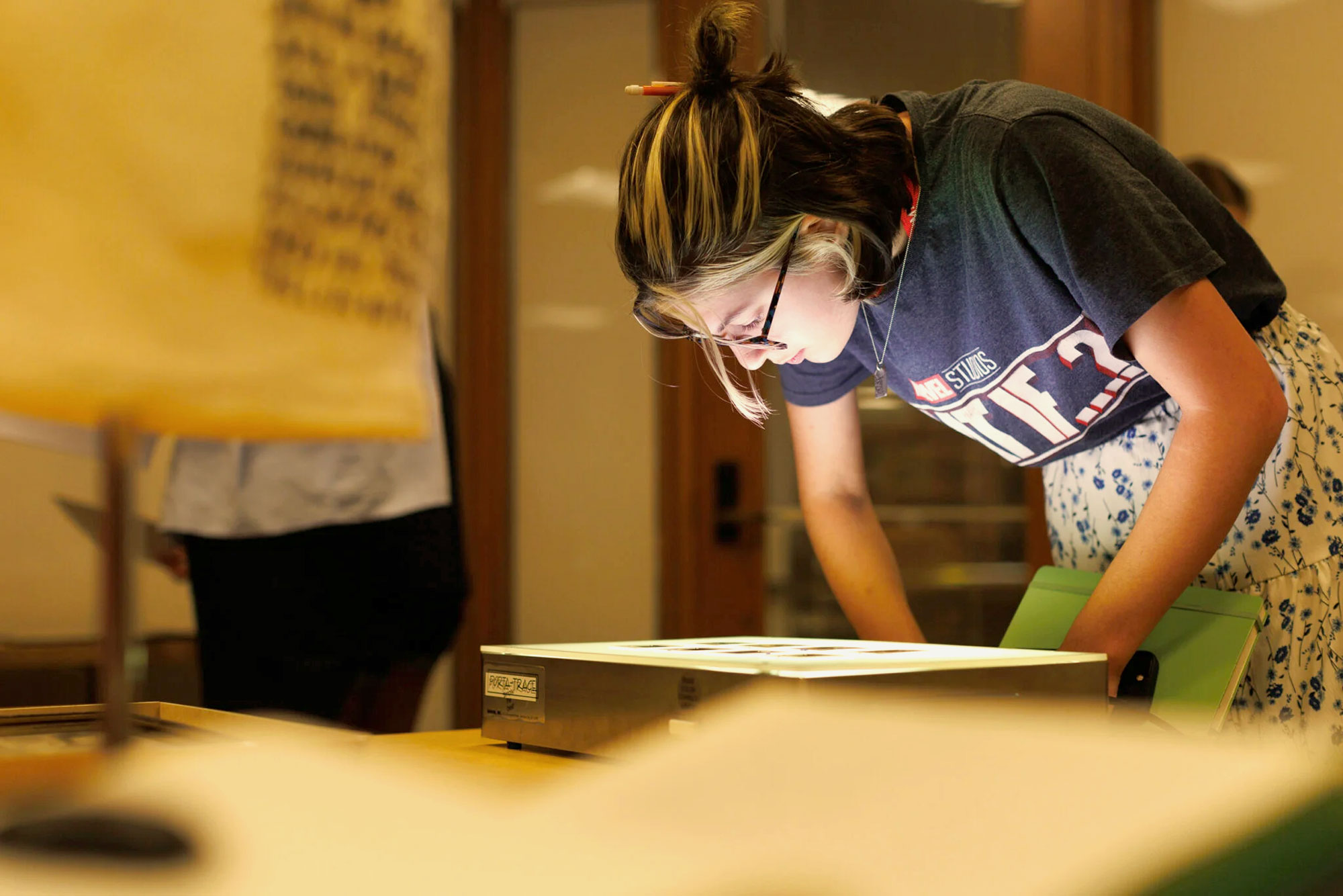 A Harvard Summer School student looks at a light box on a table.